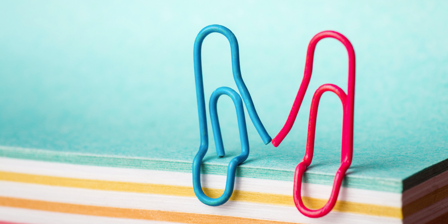 Paperclips holding hands on stack of paper